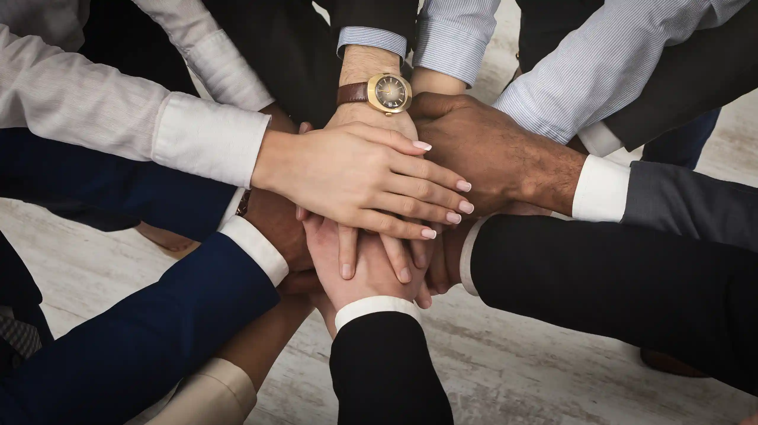 a group of business people with their hands gathered in a circle